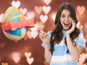 A woman is seen happy and excited pointing to an egg wrapped as a gift.