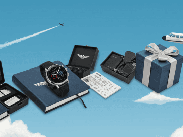 Aviation-themed gifts display against a blue sky backdrop. Features a smartwatch, notebook, sunglasses, accessories set, and a gift box with an airplane in the background.